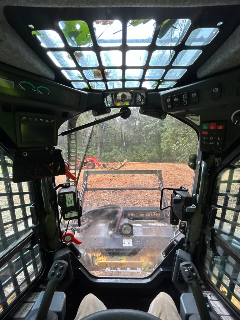 Operator view inside skid steer cab during forestry mulching job in Alabama